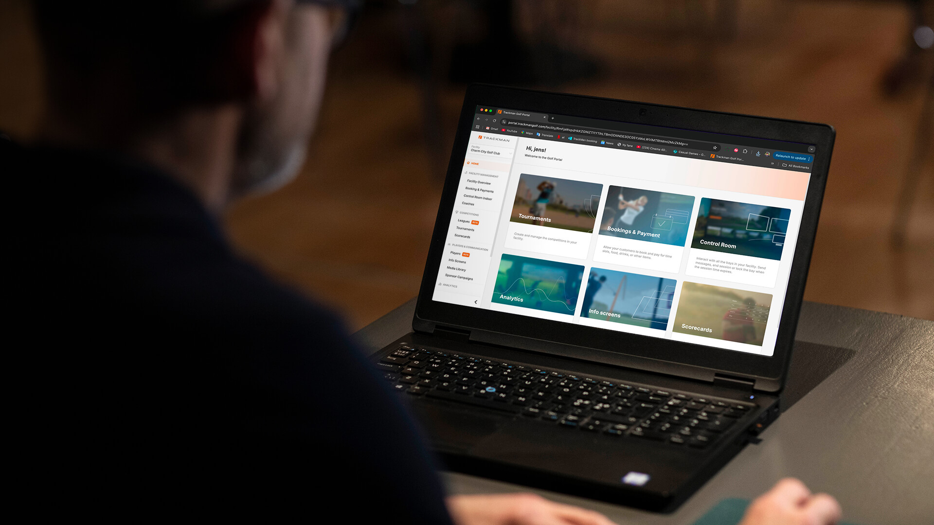Person viewing a laptop screen displaying a website with Trackman Booking & Payments