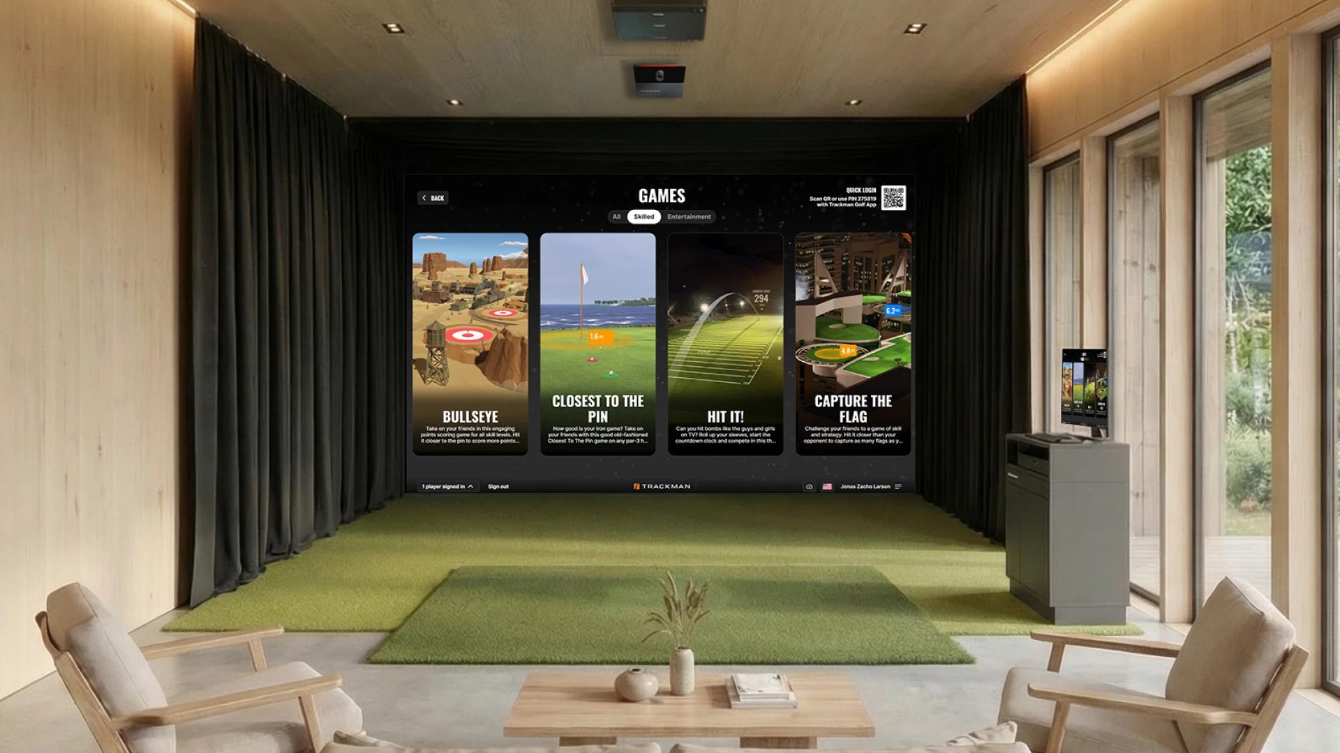 Indoor golf simulator room with a large display showcasing various golf games. Comfortable seating and a small table with decor are in the foreground.
