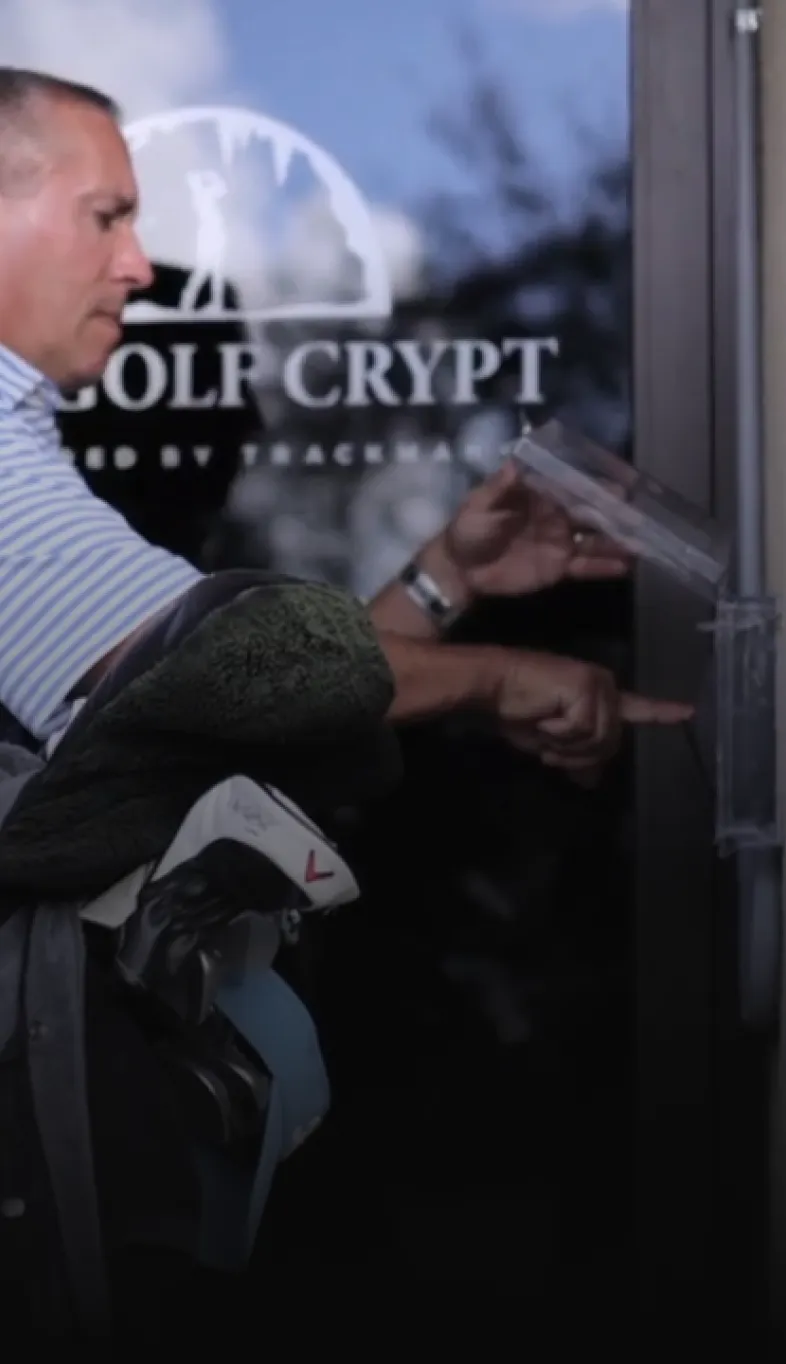 Man carrying golf clubs reaches to open a glass door labeled "GOLF CRYPT."